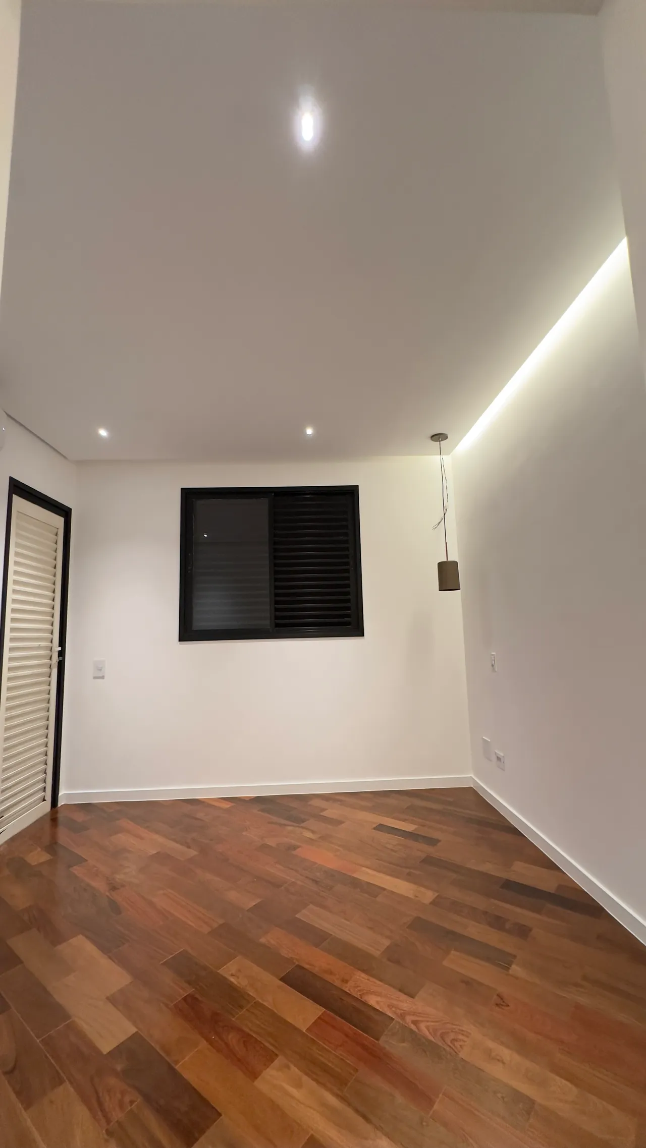 Quarto com esquadrias pretas e iluminação indireta