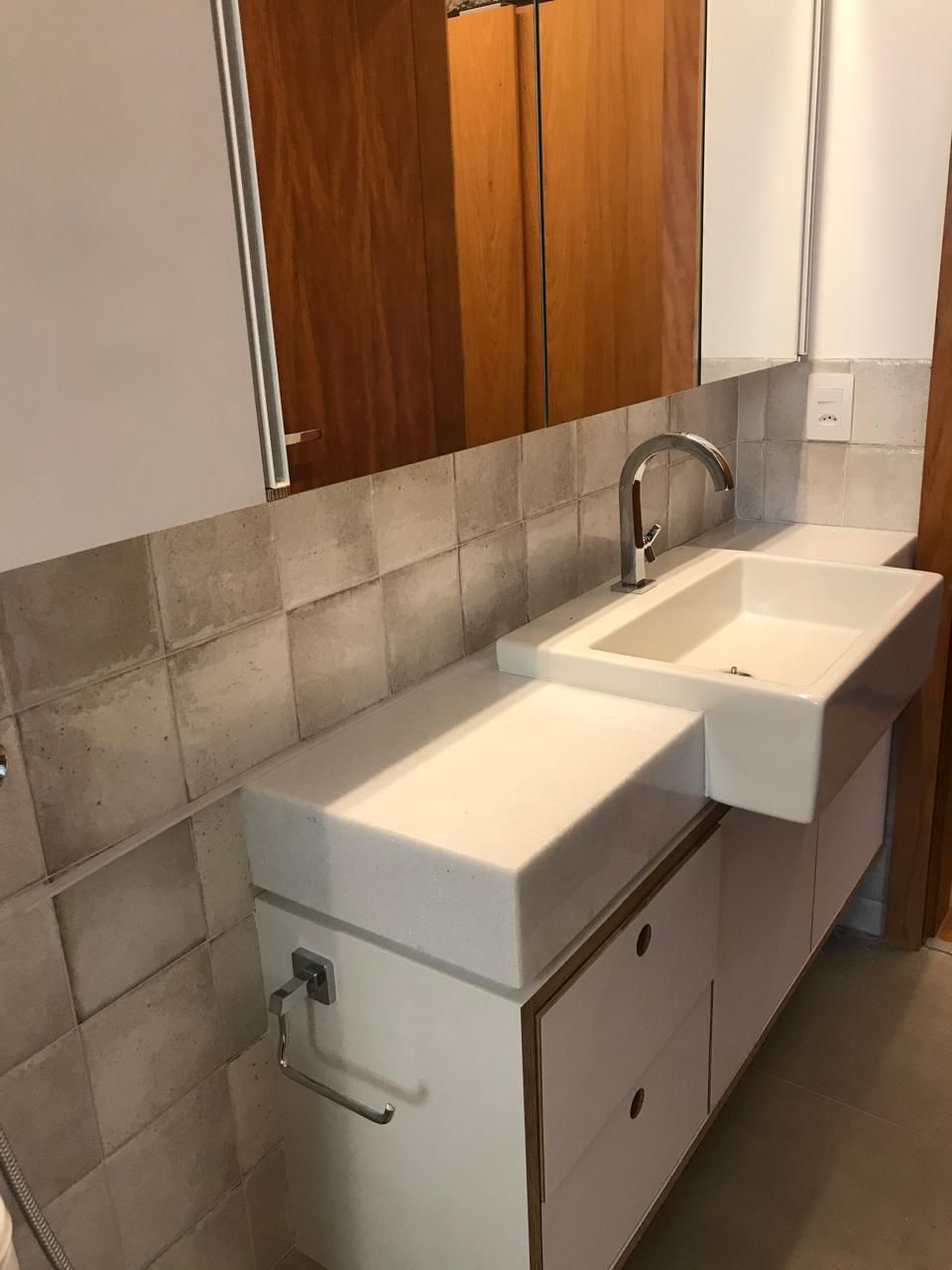 Lavabo com cuba esculpida em pedra e revestimento de cimento